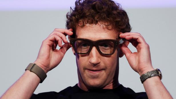 Mark Zuckerberg setzt eine braune Brille auf.