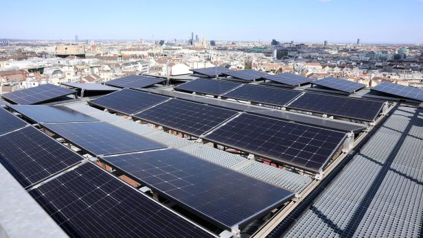 Mehrere Solarpanels auf einem Dach mit Blick über eine Stadtlandschaft bei klarem Himmel.
