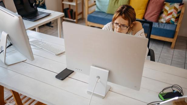 Das Bild zeigt eine Frau im Homeoffice, die sehr konzentriert auf einen Bildschirm schaut.