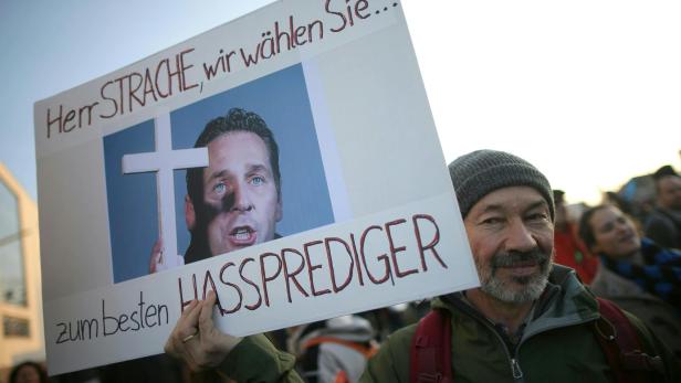 Ein Demonstrant hält ein Schild hoch mit Bild von HC-Strache inklusive Text: "Herr Strache, wir wählen Sie...zum besten Hassprediger"