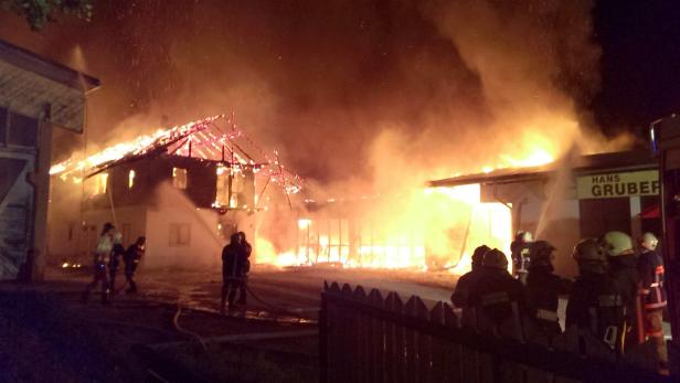 Ein Gebäude steht in Flammen, während Feuerwehrleute versuchen, das Feuer zu löschen.