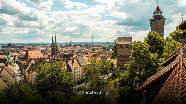 Blick über die Dächer der Nürnberger Altstadt mit Kaiserburg und Kirchtürmen bei Tageslicht.