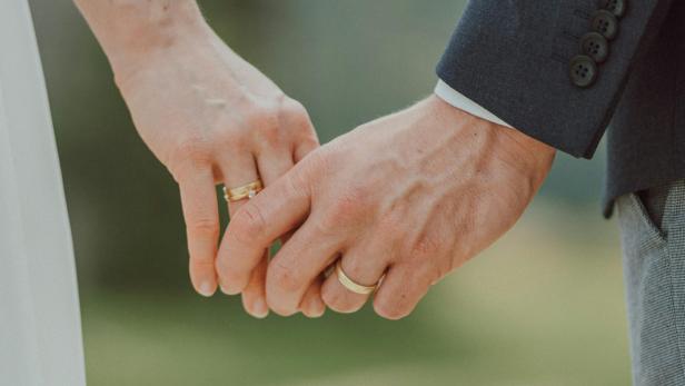 Eine Nahaufnahme eines Hochzeitspaares, die sich an den Händen halten