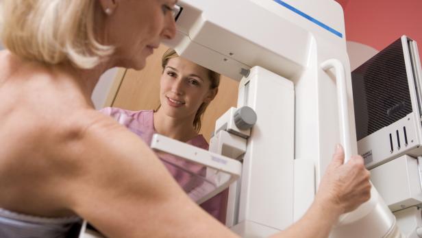 Nurse helping an older patient undergoing a mammogram