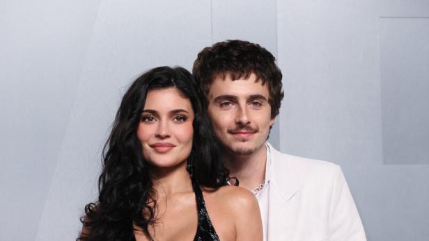Timothée Chalamet und Kylie Jenner sind elegant gekleidet, stehen eng nebeneinander und lächeln.