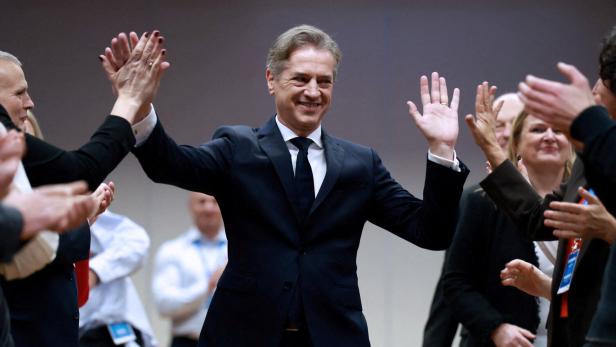 Ein Mann im Anzug hebt jubelnd die Arme