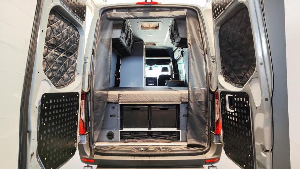 Blick in den modular ausgebauten Innenraum eines Mercedes Sprinter Campervans mit Stauraum.