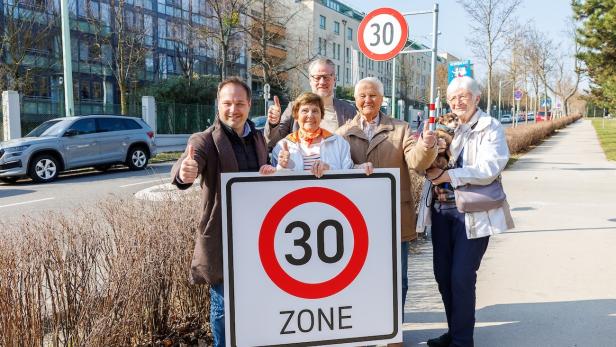 Bezirksvorsteher Daniel Resch und Senioren stehen mit einem Temp-30-Schild und Daumen hoch auf der Straße.