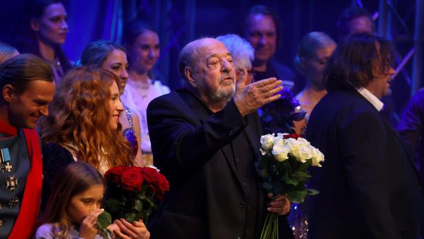 Auf der Bühne stehen Darsteller mit Blumensträußen, Ralph Siegel gestikuliert ins Publikum.