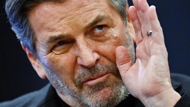 Thomas Anders mit grau meliertem Haar hält die Hand hoch.