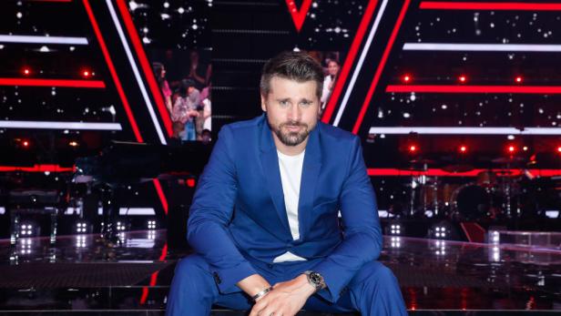 Thore Schölermann lächelt im blauen Anzug auf der Bühne.