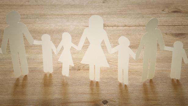 concept image of Family paper chain cutout holding hands, over wooden table