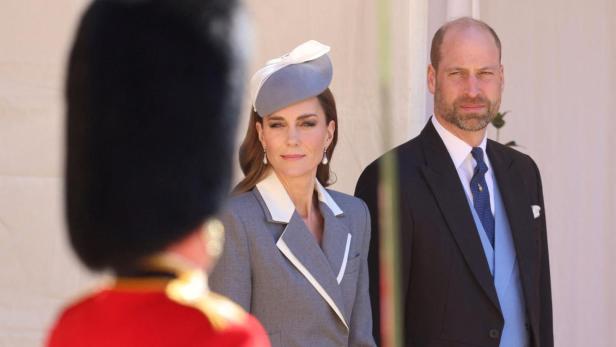 Kate und William stehen formell gekleidet vor einem Gebäude.