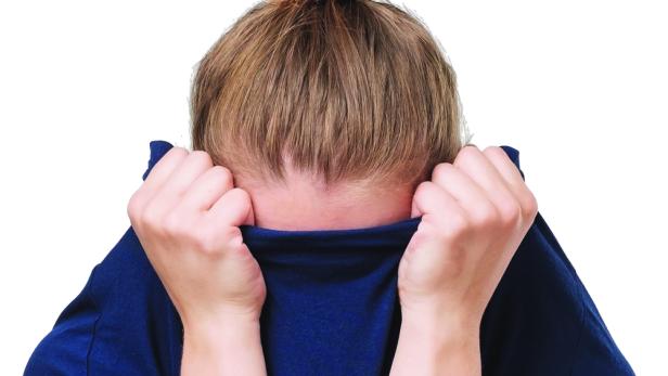 Eine Frau versteckt ihr Gesicht unter einem Pullover.