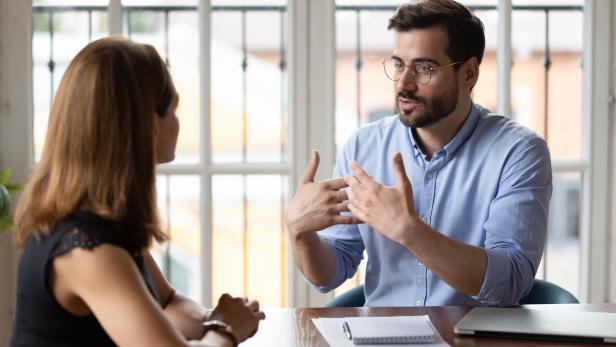 Leader in eyeglasses explaining project details to new female employee.