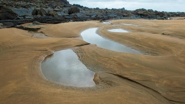 ein großes felsiges Gebiet mit Sand und Wasseransammlungen