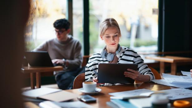 Students Studying and Working on Technology in a Relaxed Cafe Setting