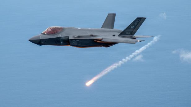 Ein Kampfjet fliegt über das Meer und feuert einen Täuschkörper ab