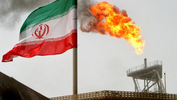 FILE PHOTO: A gas flare on an oil production platform is seen alongside an Iranian flag in the Gulf