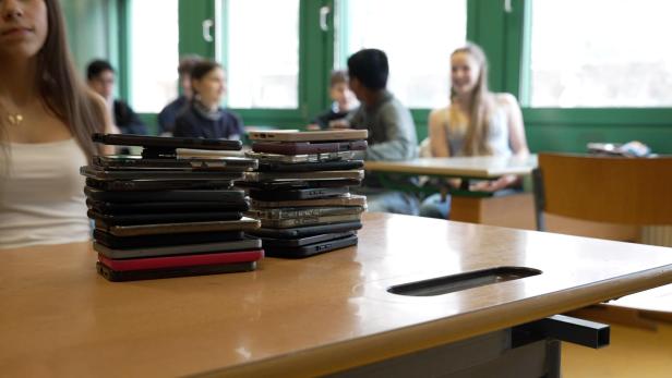Ein Stapel Smartphones auf einem Tisch in einem Klassenzimmer