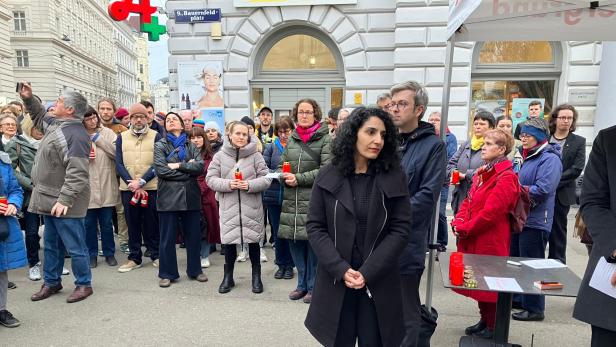 Menschen versammeln sich mit Kerzen zu einer Gedenkveranstaltung am Bauernfeldplatz.