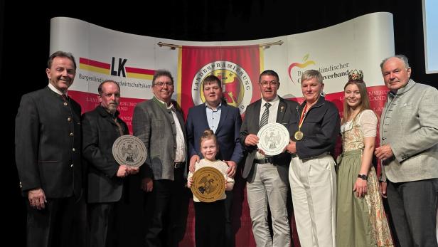 Eine Gruppe von Personen, darunter ein Kind, posiert mit Auszeichnungen vor einem Banner der Landwirtschaftskammer Burgenland.