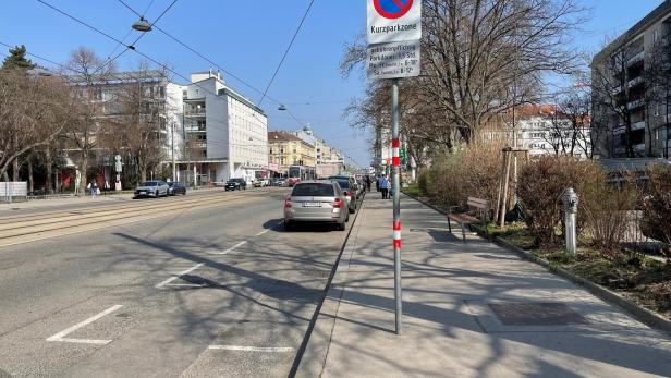 Eine Straße in Wien mit geparkten Autos und einem Kurzparkzonen-Schild.