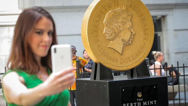 FILE PHOTO: A woman takes a selfie with the world's  largest gold bullion coin, the Australian Kangaroo One Tonne Gold Coin, is displayed outside the NYSE in New York