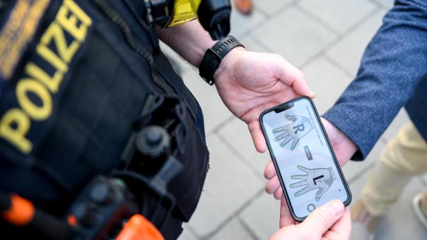 Polizist scannt Fingerabdrücke mit einem Smartphone auf offener Straße.