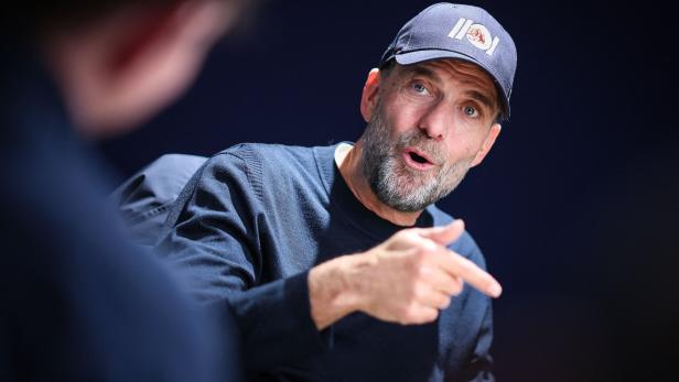 Jürgen Klopp trägt eine dunkle Kappe und einen Pullover, während er gestikulierend in einem Gespräch spricht.