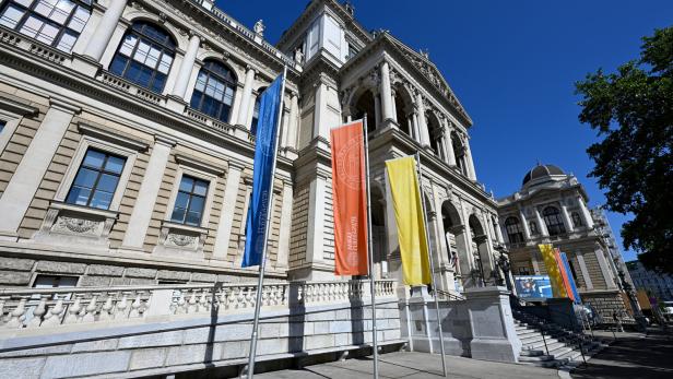 Vor der Universität Wien wehen blaue, orangefarbene und gelbe Flaggen.