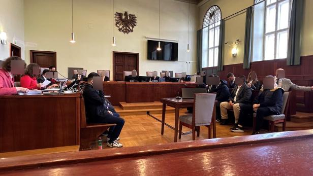 Angeklagte, Verteidiger, Richter und Dolmetsch im Gerichtssaal.