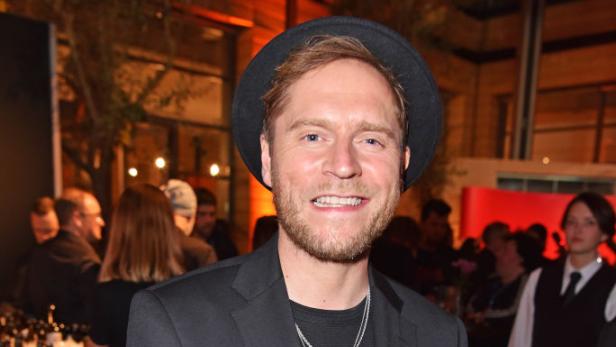 Johannes Oerding im schwarzen Anzug mit schwarzem Hut auf einem Event.