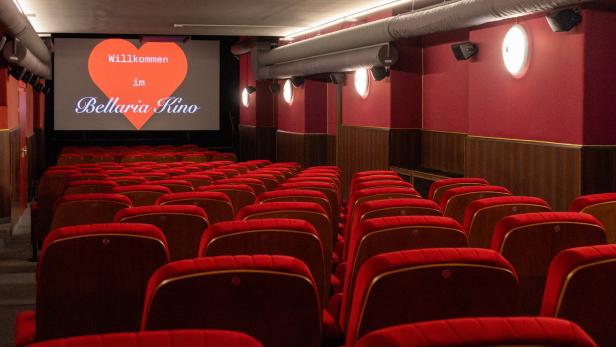 Ein Kinosaal mit roten Sitzmöbeln und einer Leinwand