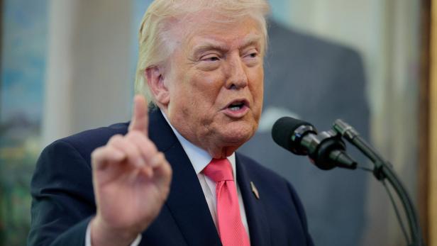 Donald Trump spricht an einem Mikrofon und hebt warnend den Zeigefinger.