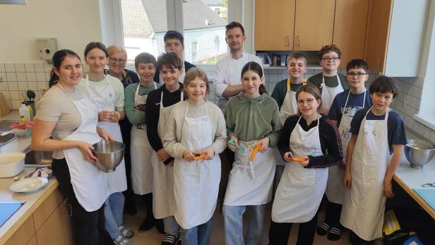 Kinder mit einem Koch in einer Küche.