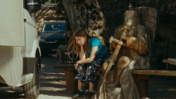 Eine junge Frau sitzt auf einer Bank.