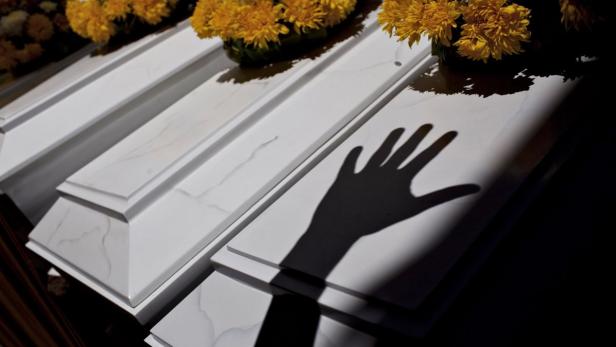 The shadow of a relative&#039;s hand is projected onto the coffins of victims, killed in massacres executed by Shining Path militant group and the army in Peru&#039;s southern district of Chungui between 1984 and 1985, during a funeral ceremony in Ayacucho city January 25, 2013. The remains of 78 people from several villages in the district of Chungui were found in more than 50 mass and individual graves after exhumations works done since 2011. The victims, including pregnant women, children and elder people were killed by Shining Path militant group and the army during the 1980-2000 Civil War in Peru and were delivered to their families for burial on Friday. Picture taken January 25, 2013. REUTERS/Musuk Nolte (PERU - Tags: CIVIL UNREST CRIME LAW OBITUARY TPX IMAGES OF THE DAY)