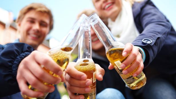 Jugendliche stoßen mit drei Flaschen miteinander an.