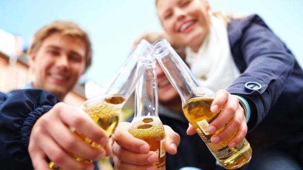 Jugendliche stoßen mit drei Flaschen miteinander an.