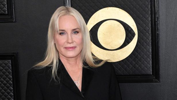 Daryl Hannah mit blonden Haaren trägt einen schwarzen Blazer und eine gestreifte Strumpfhose.