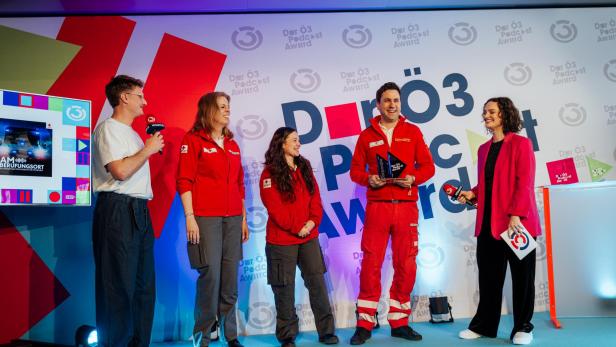 Zwei Ö3 Sprecher stehen mit drei Personen vom Rotes Kreuz NÖ Team vor einem Ö3 Hintergrund.