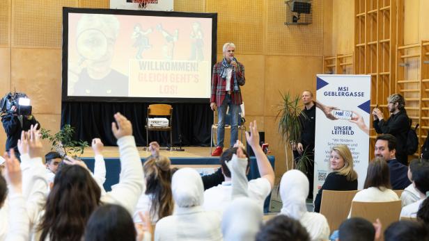 Thomas Brezina auf der Bühne, mehrere Jugendliche im Publikum zeigen auf. 