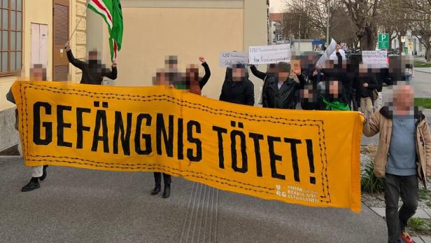 Mehrere Personen tragen ein Banner mit der Aufschrift "Gefängnis tötet" bei einer Demo.