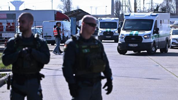 Zwei Beamte der ungarischen Spezialeinheit TEK, dahinter die beiden beschlagnahmten Geldtransporter.