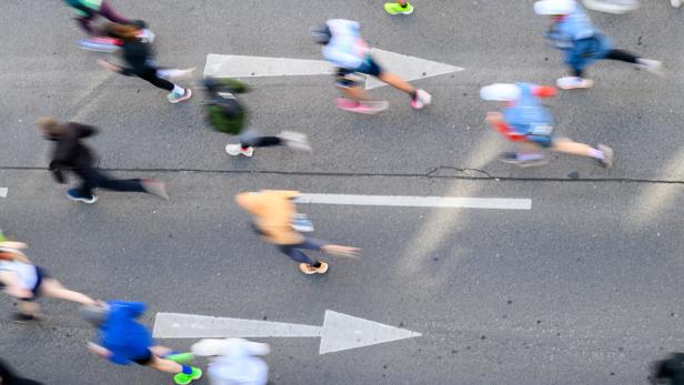 Läufer bewegen sich verschwommen auf einer Straße mit Richtungspfeilen.