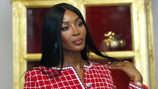 Naomi Campbell trägt ein rot-weißes Tweed-Jackett und eine goldene Halskette.