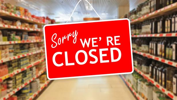 Ein rotes Schild mit der Aufschrift "Sorry, we're closed" hängt in einem Supermarktgang.
