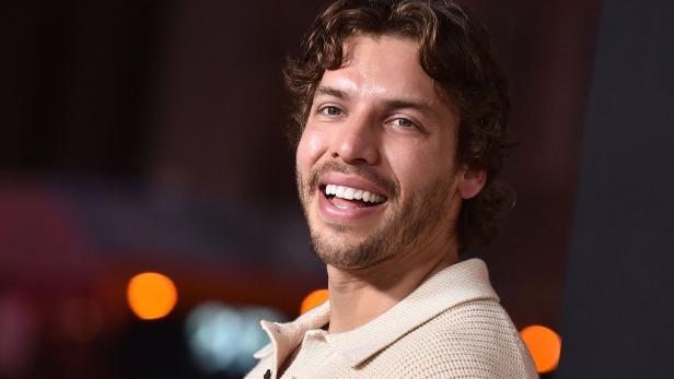 Ein lächelnder Joseph Baena mit braunen Locken und Bart trägt einen hellen Strickpullover.