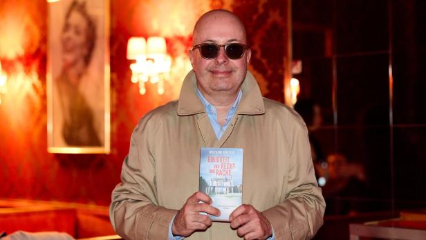 Ein Mann mit Sonnenbrille hält Wolfgang Ainetters Buch "Einigkeit und Recht und Rache" in den Händen.